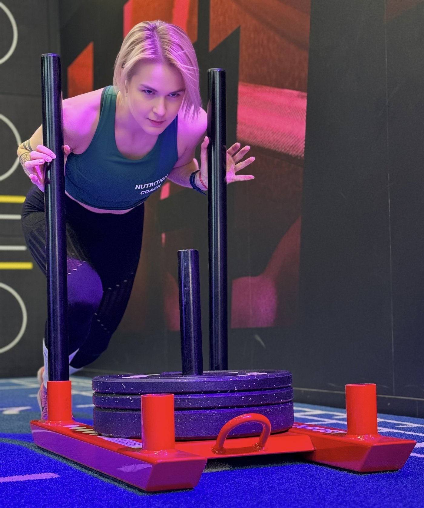 Olga pushing a loaded sled during a gym workout