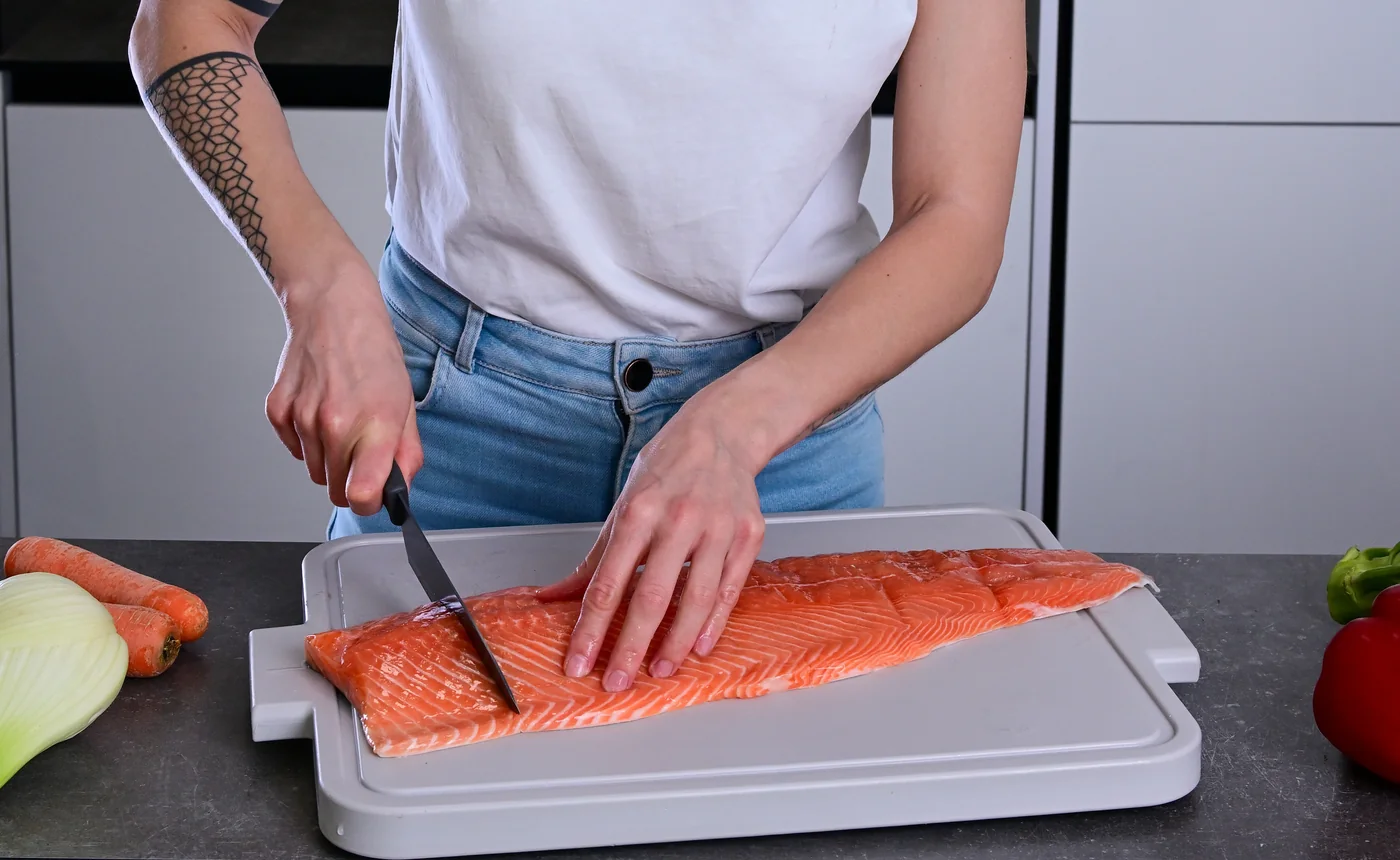 Olga preparing fresh salmon with vegetables in a kitchen