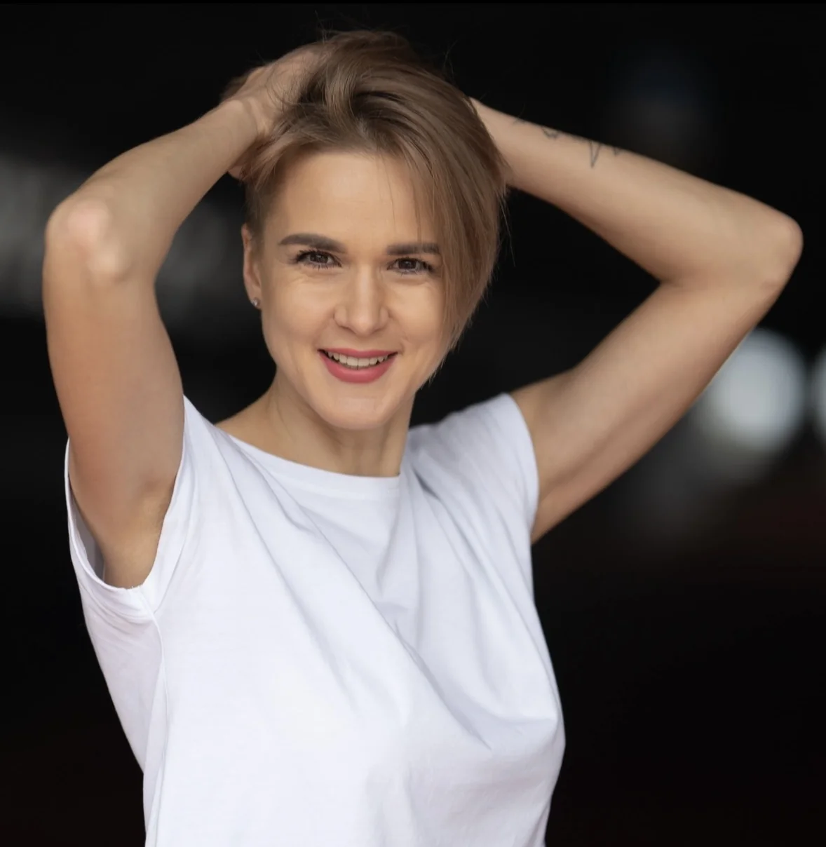 Portrait of Olga smiling warmly, wearing a white t-shirt